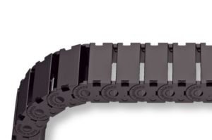 A close-up of the MONO 0180.10 cable drag chain, featuring interlocking rectangular segments with rounded edges, shown bending at a right angle.