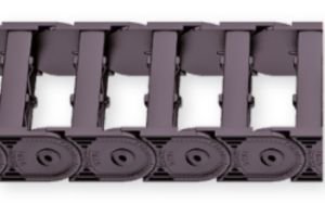 Close-up of a black plastic UA1665-020-050 Kabelschlepp cable carrier chain with linked rectangular sections and circular pivots, used to organize and protect cables or hoses in moving machinery. Close-up of a black plastic UA1665-020-050 Kabelschlepp cable carrier chain with linked rectangular sections and circular pivots, used to organize and protect cables or hoses in moving machinery.